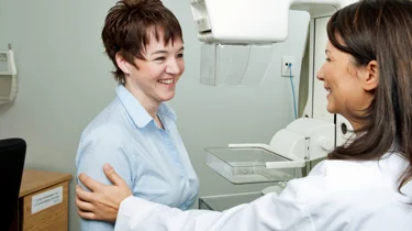 Smilende læge og patient fører en samtale.