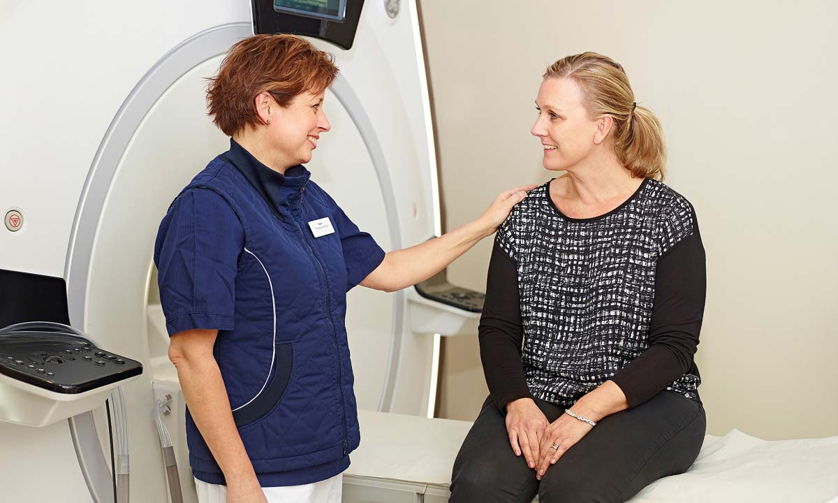 Læge og patient smiler ved en magnetkamera.