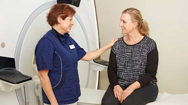 Læge og patient smiler ved en magnetkamera.