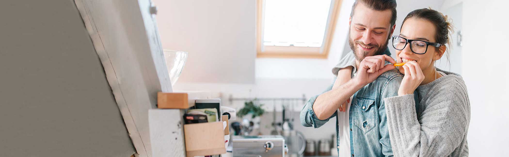 Glad mand og kvinde står i køkkenet og laver mad.