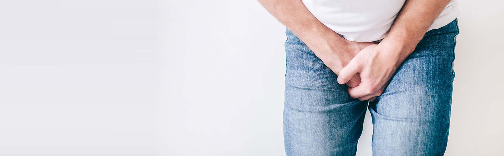 En mand oplever smerter og betændelse omkring urinrøret, og holder sig derfor om skridtet.