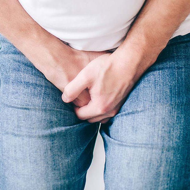 En mand oplever smerter og betændelse omkring urinrøret, og holder sig derfor om skridtet.