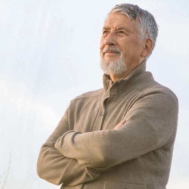 En mand står eftertænksomt og kigger ud.