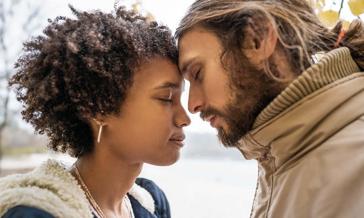 En ung kvinde og mand står med hovederne tæt sammen.