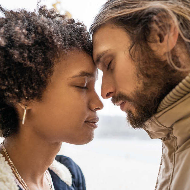 En ung kvinde og mand står med hovederne tæt sammen.